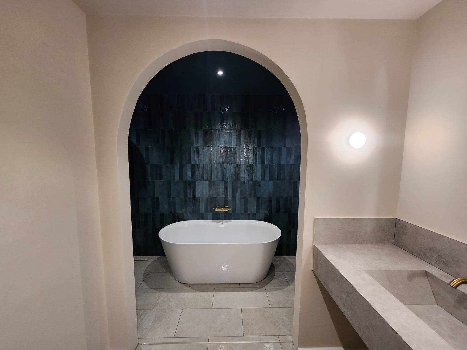 Bathroom renovation in Marbella: freestanding bath in an arched alcove lined with glazed blue tile
