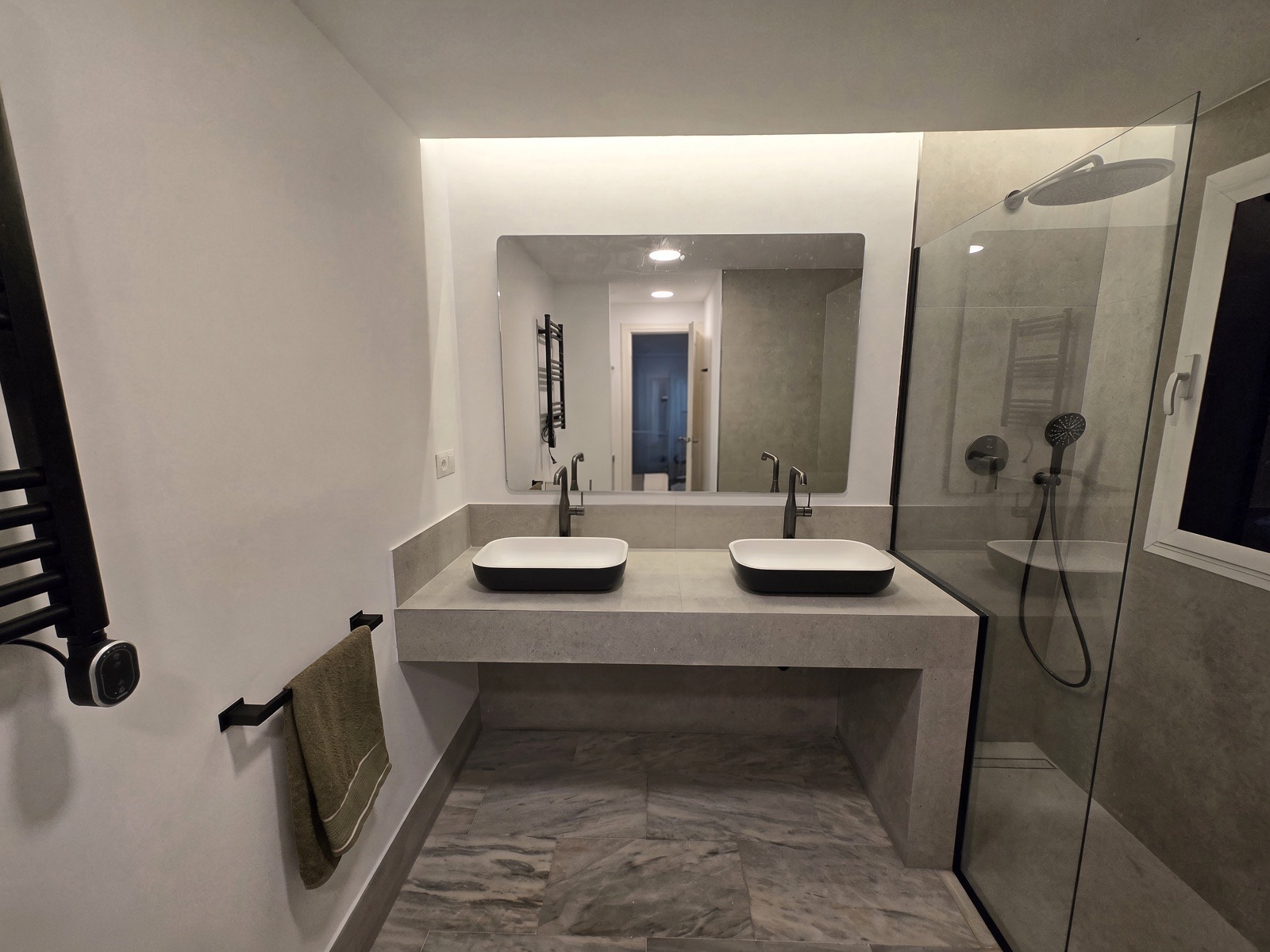 The finished grey bathroom: vanity, lit mirror and walk-in shower