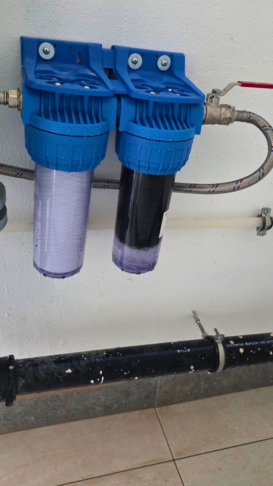 Sediment cartridge and carbon cartridge in their two blue housings on the wall